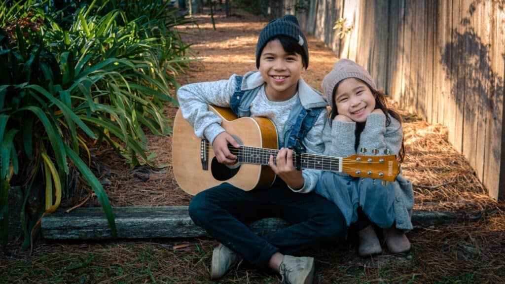 kid playing beginner travel guitar with small hands