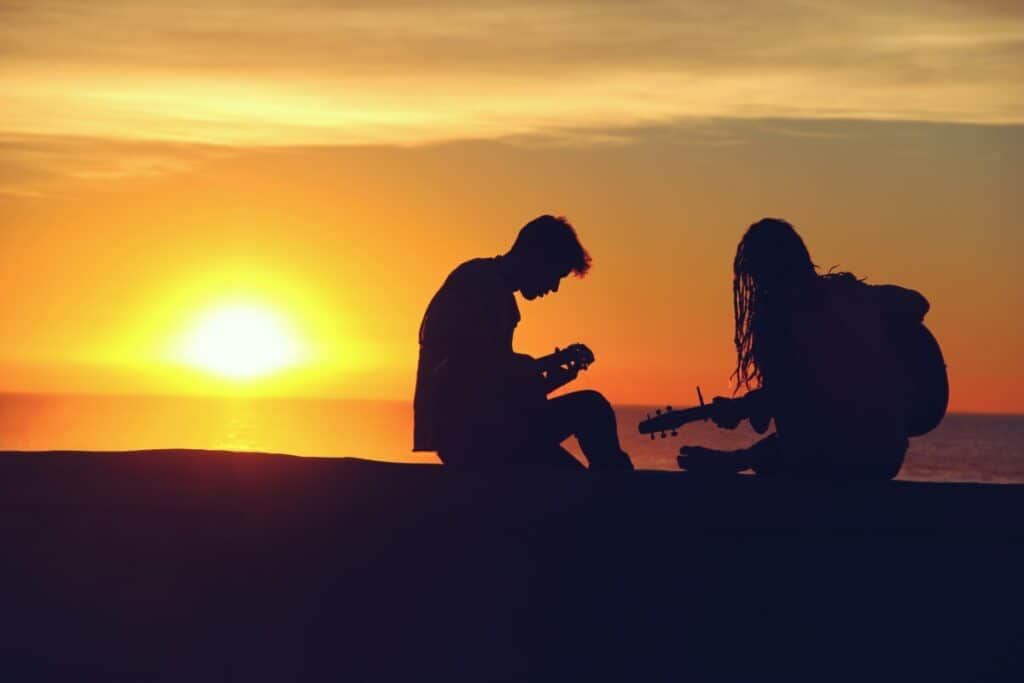 silhouette of attractive man and woman playing guitars