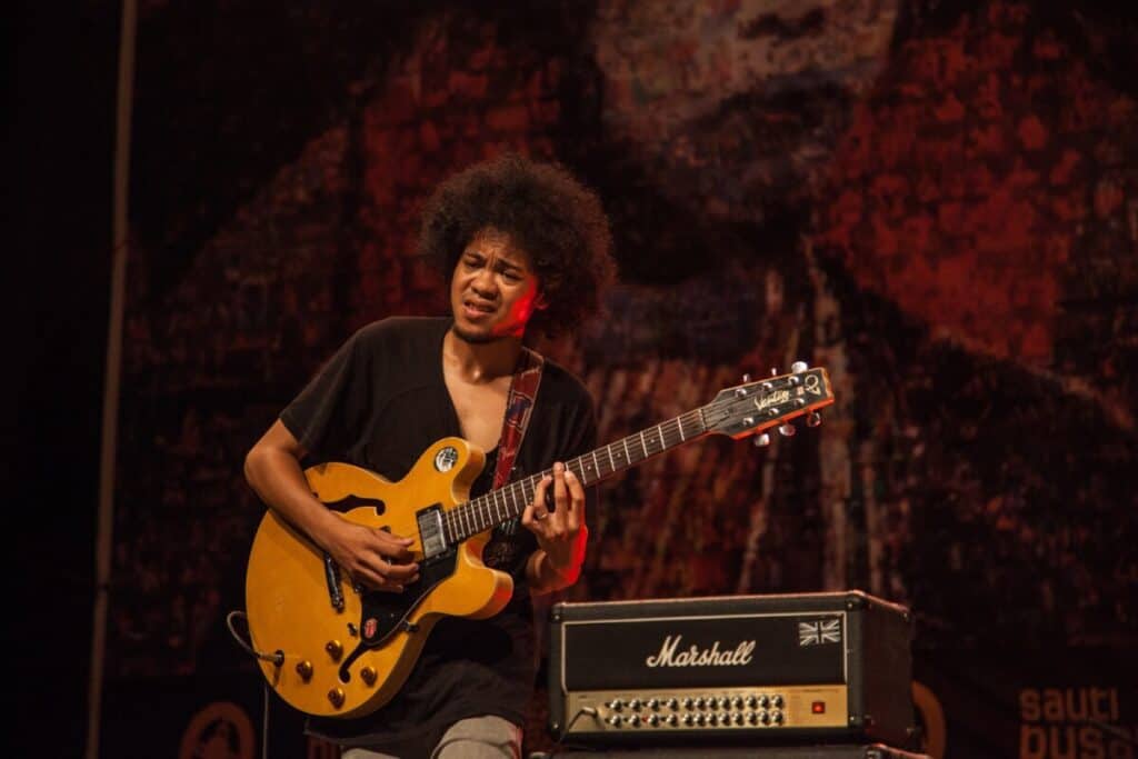 man playing brown and black electric guitar