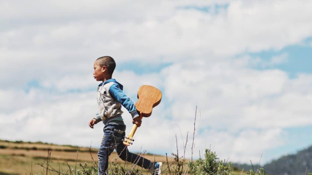 boy running while holding guitar